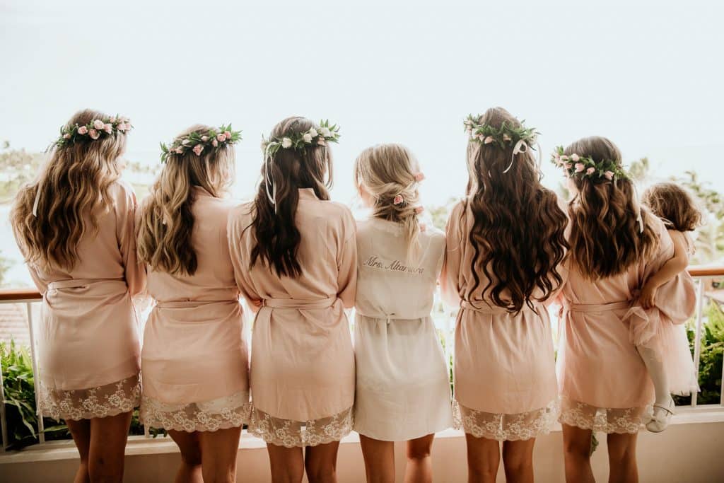 Bride and bridesmaids wearing custom robes looking out on balcony of Four Seasons Koolina