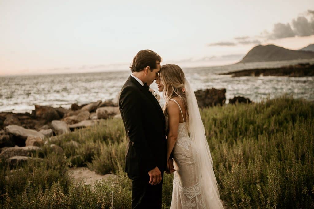 Bride and Groom touching foreheads in romantic shot at Secret beach between Four Seasons Resort Koolina and Lanikuhonua