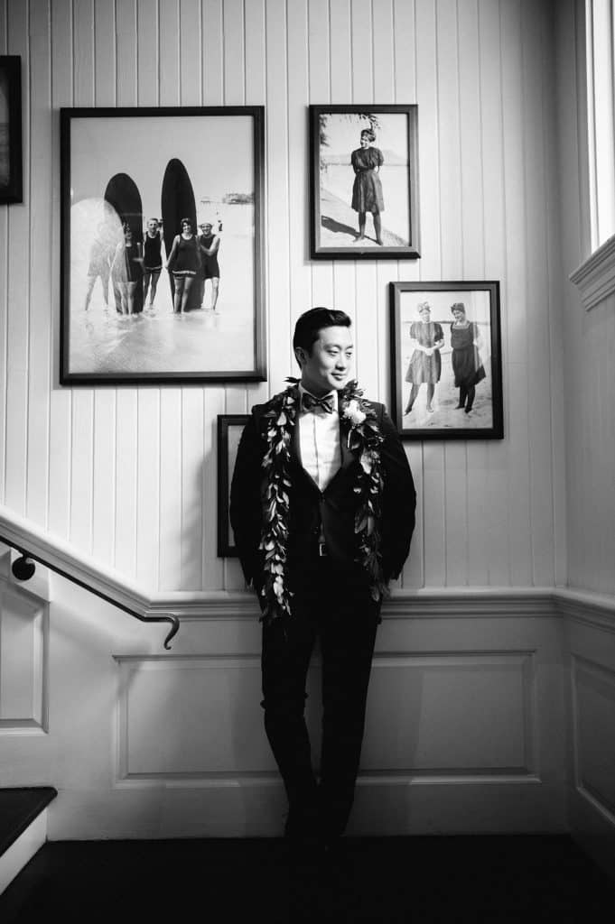 Black and White Portrait of Groom amongst classic photos of Waikiki on Moana Grand Staircase