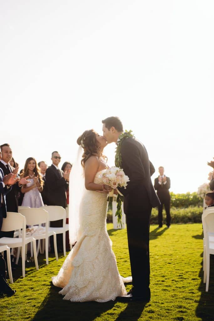Bride and Groom kissing on lawn at four seasons resort oahu at kaolin