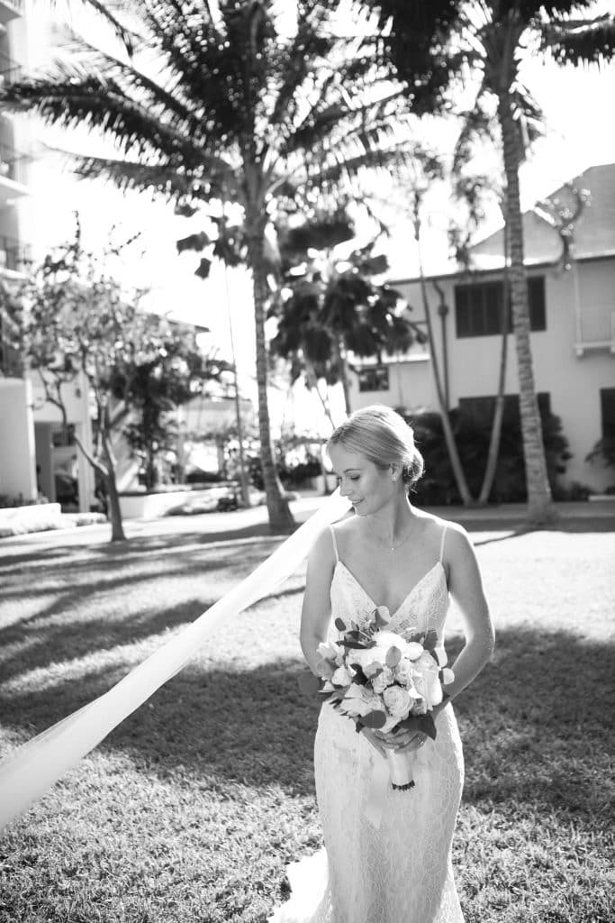 Black and White image of Bride walking in Halekulani Courtyard with veil blowing in wind