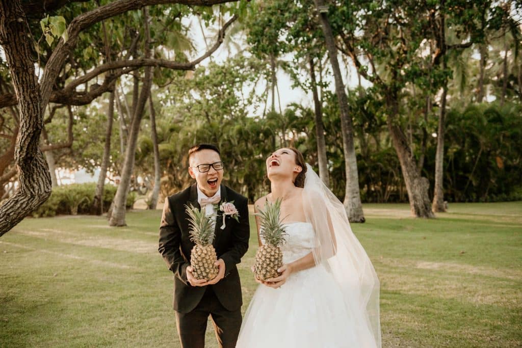 Bride and Groom holding Pineapples while laughing
