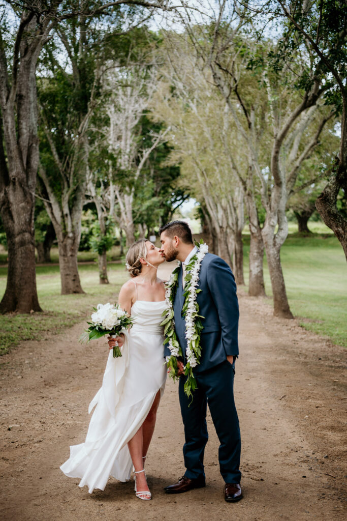 Bride and groom kissing in front of famous row of trees at Dillingham Ranch