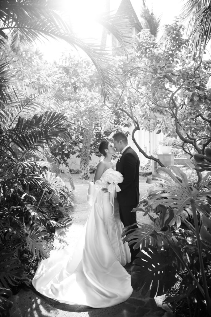 Black and White image of bride and groom kissing in lush greenery at the Four Seasons Oahu