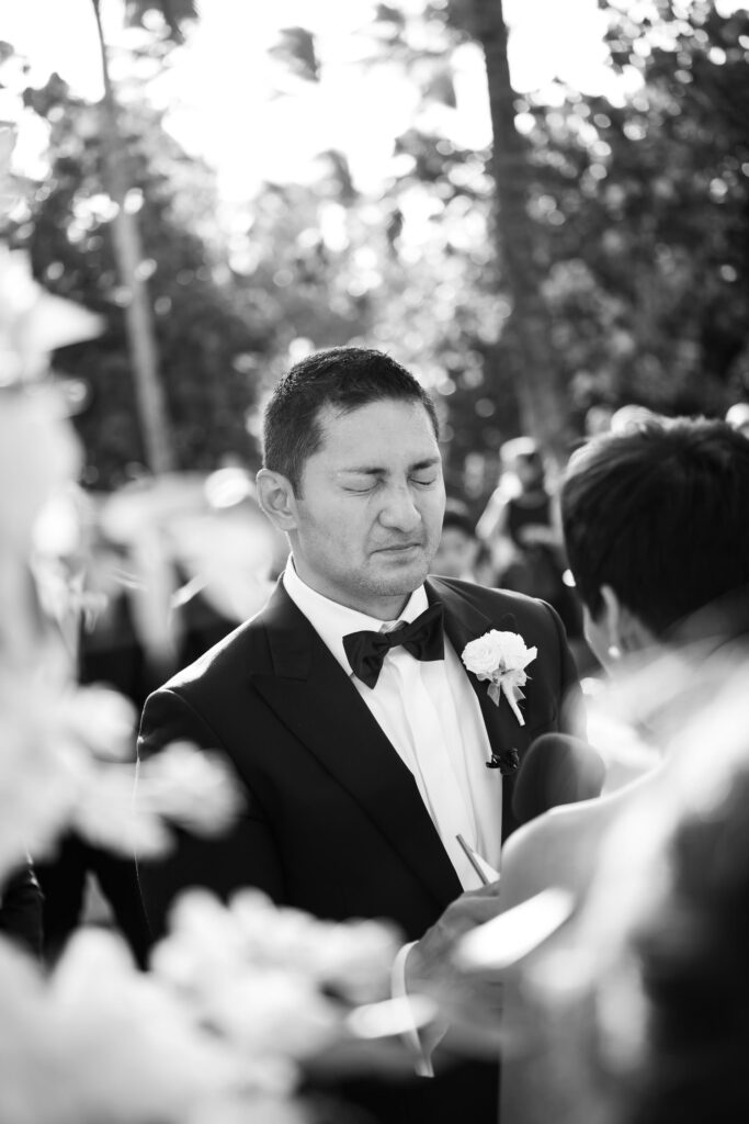 Black and White image of wedding ceremony at Lurline Lawn, groom reacting to bride.