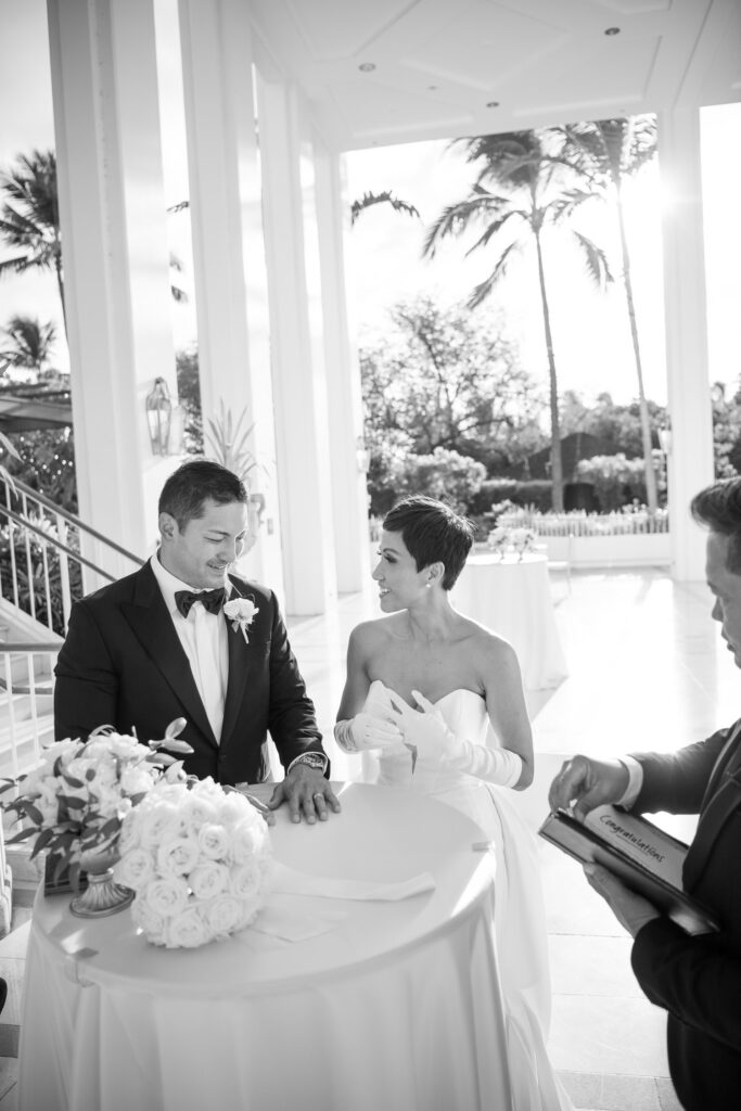 Black and White image of bride and groom signing marriage certificate.