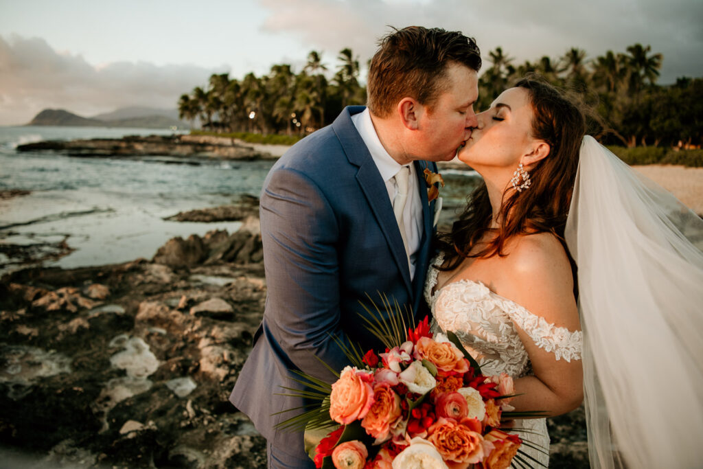 Groom kissing Bride with Waianae Mountains in the background.