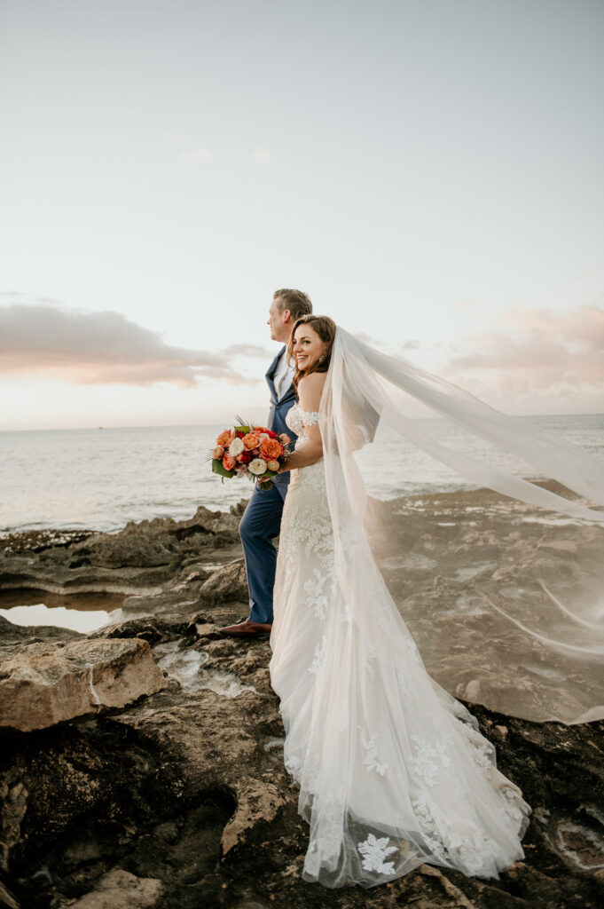 Bride and Groom at Secret Beach at sunset in front of Four Seasons Resort Oahu at Koolina.