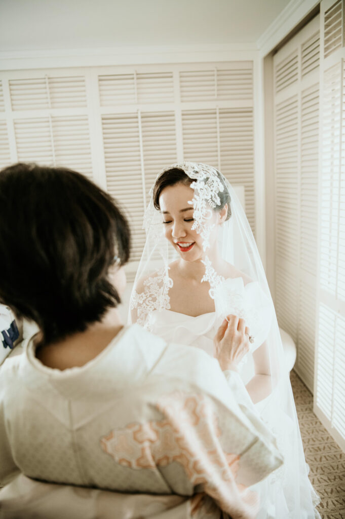 Mother of bride putting on veil for her daughter.