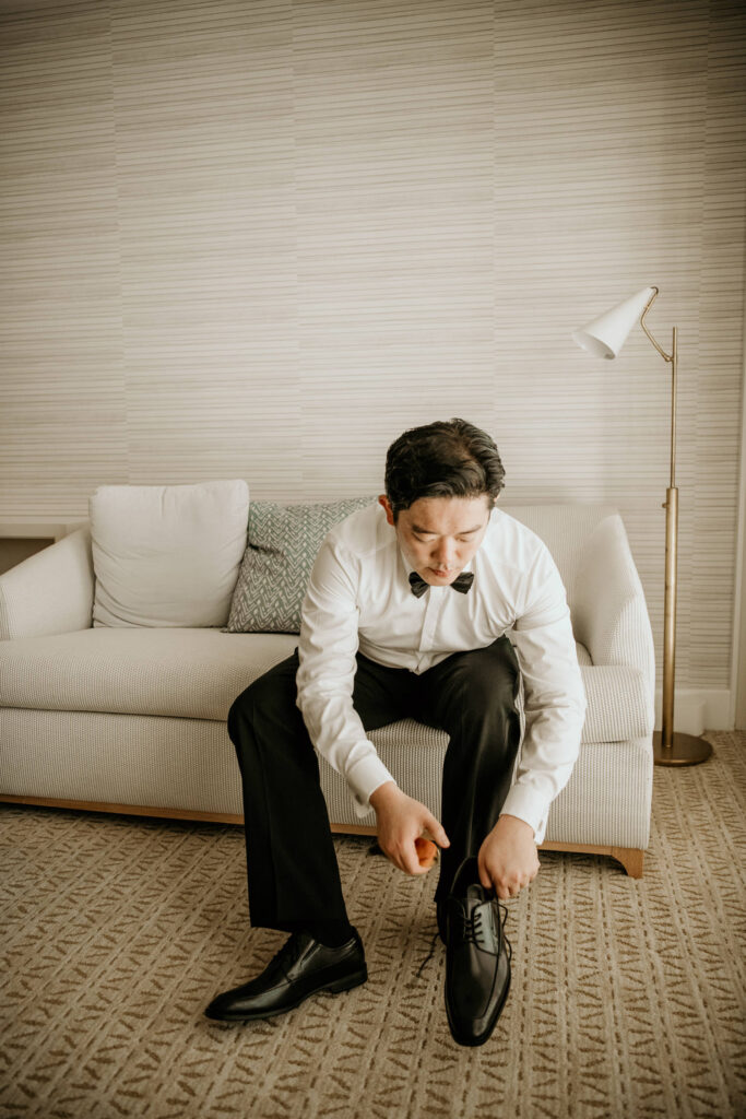 Groom putting on his shoes in the Halekulani Suite.