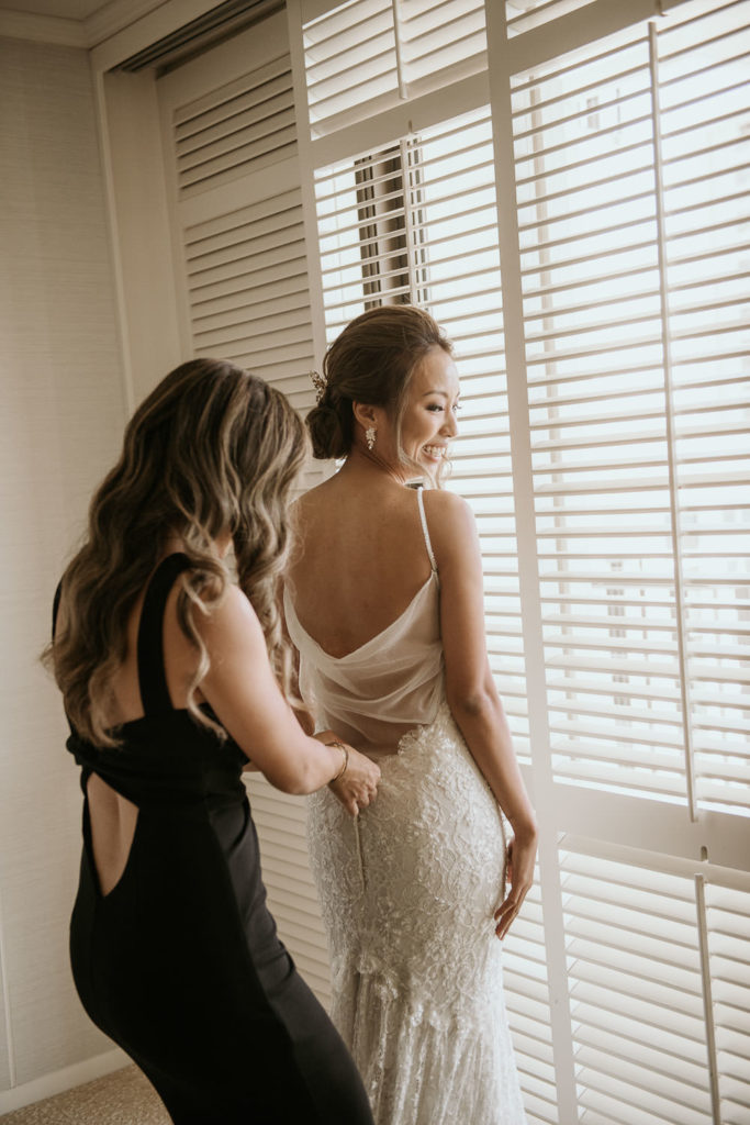 Maid of Honor helping Bride into dress