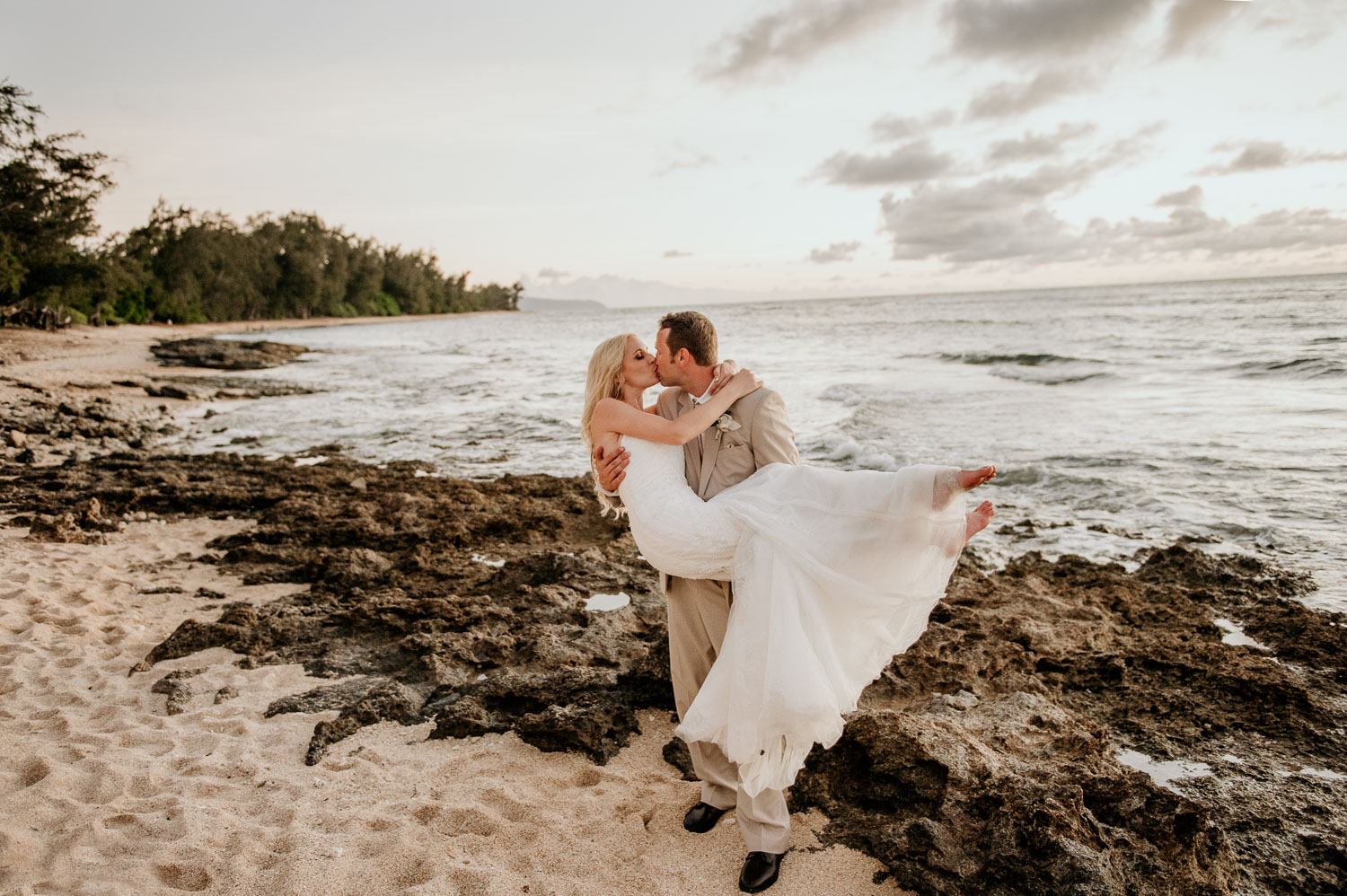 Bride and Groom kissing at beach by Loulu Palm Estate