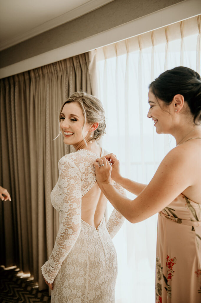 Maid of Honor helping bride into her dress at the Moana Surfrider.