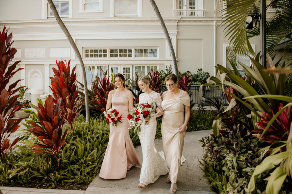Bride and her mother and sister walking down the aisle at the Diamond Head Lawn of the Moana Surfrider.