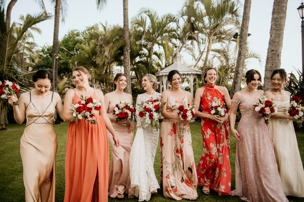 Bridesmaids in colorful dresses walking with bride on the Diamond Head Lawn.