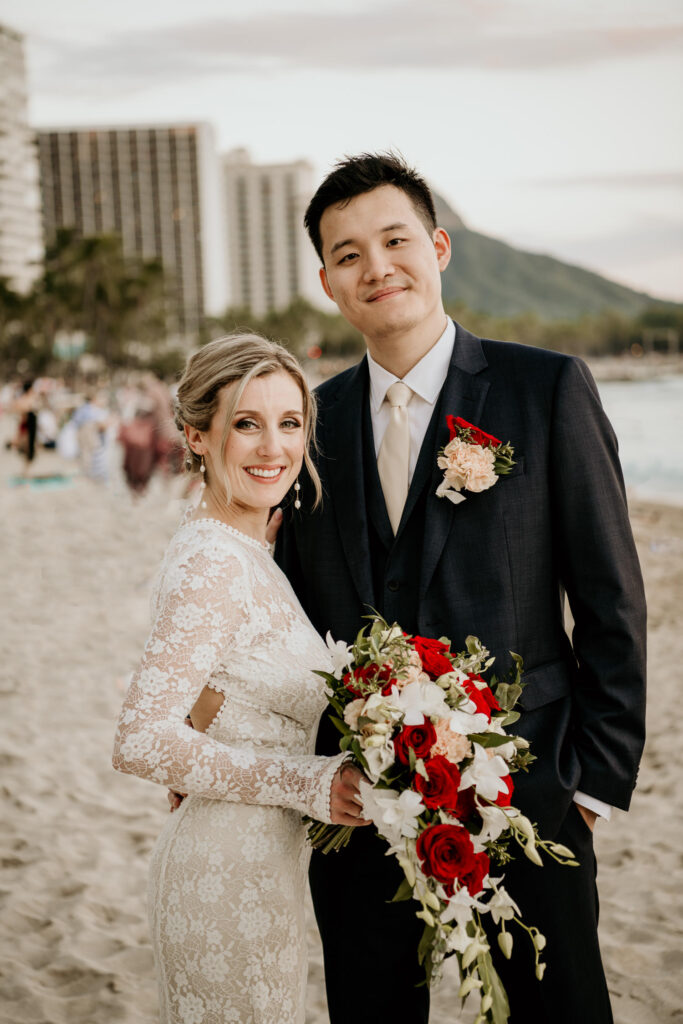 Tall groom with bride on Waikiki Beach with Diamond Head in the background.