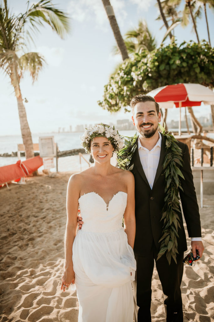 Bride and Groom on Waikiki Beach holding face coverings